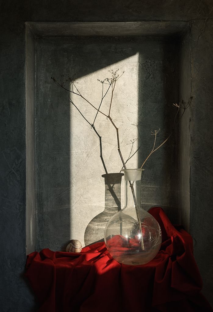 Glass vessel and dried branches in a stone window frame